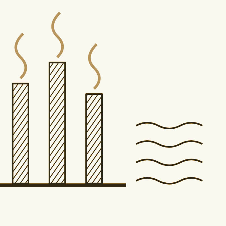 Three factory chimneys with rising smoke beside a wavy sea